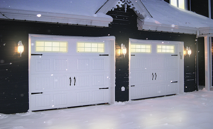 Traditional style blue house in winter, with double garage having 9' x 7' Standard+ North Hatley SP Ice White garage doors.