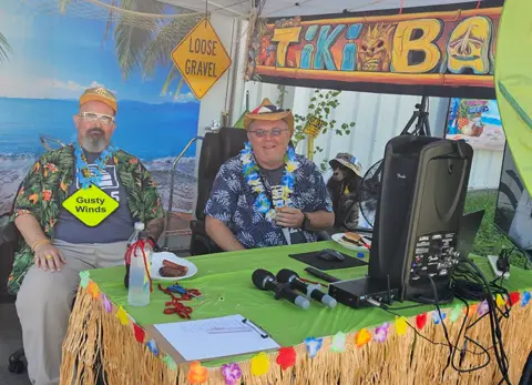 Garaga employees from Ponca City facility in Oklahoma in Hawaiian shirts sit at a tiki bar booth.