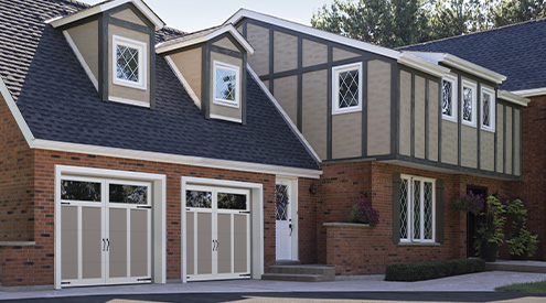 Craftsman-style house in brick with wood accents and dormer windows. Garage doors: Eastman E-12, 8' x 7', Claystone doors and Ice White overlays, Panoramic Clear windows.