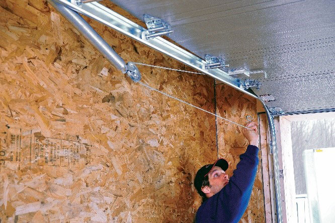 Installateur de portes de garage qui termine l’installation d’un système de ferronnerie