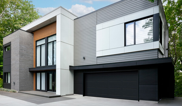 Modern house, square shapes, showcasing different volumes and textures, black 2-car garage door in Vog design