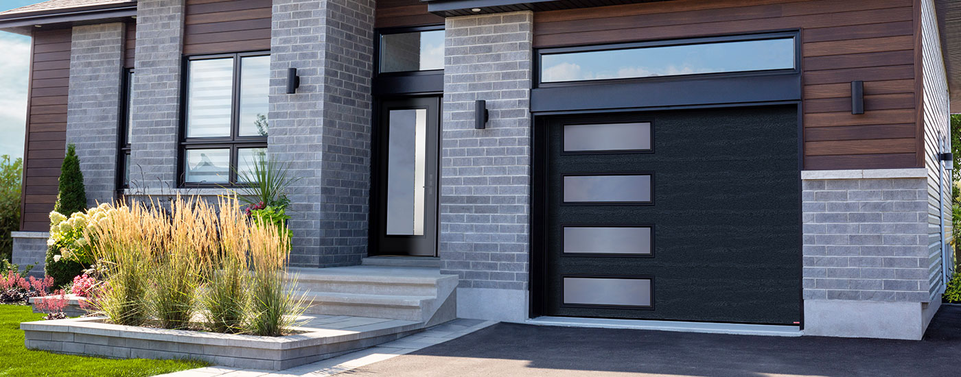 Single-storey modern house, pale grey brick and Cognac wood, attached garage, Black garage door, Harmony windows with Grey Sandblasted glass