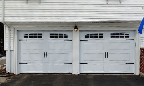White house with North Hatley garage doors, 9' x 7', Ice White, windows with Double Stockton Arch Inserts