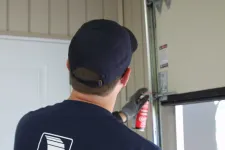 Un technicien certifié en train de lubrifier les roulettes d'une porte de garage