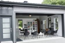 Garage converti en un charmant salon de coiffure professionnel avec une salle d'attente, 2 stations de coiffure et un espace de rangement pour les produits capillaires.