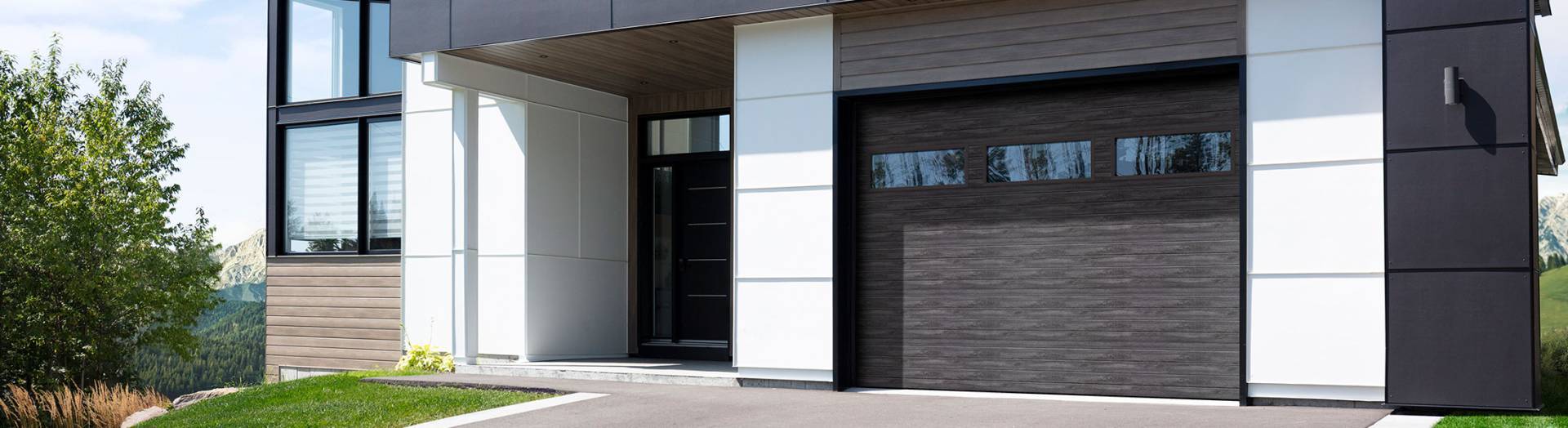 Maison moderne, bois cendré, fibrociment blanc, fenêtre et porte noirs, porte de garage Gris patiné, similibois