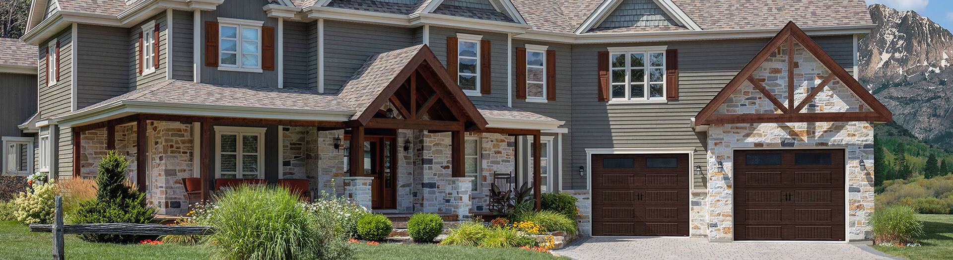 Luxurious Transitional Exterior Home Design. 2-storey home, gray siding, stone and wood with 2 single garage door in Dark Walnut color