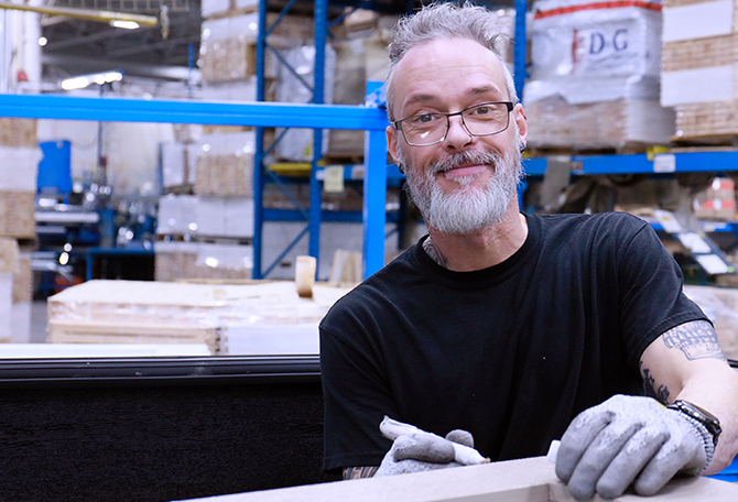 Journalier souriant travaillant le bois dans l'usine Garaga à Saint-Georges