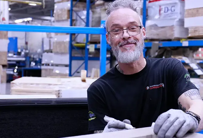 Journalier souriant travaillant le bois dans l'usine Garaga à Saint-Georges