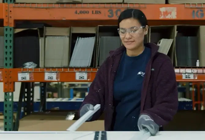 Employée manipulant des moulures de porte de garage sur la chaîne de production chez Garaga