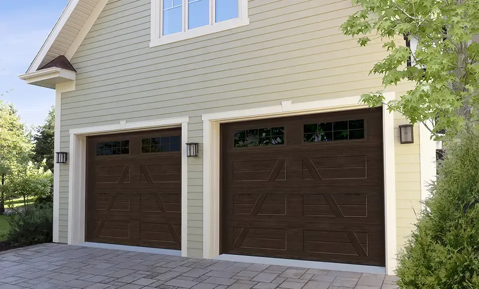 A traditional farmhouse with 2 Garaga singles garage doors, Village Collection, A Layout, 2-Slat Base, in Dark Walnut Faux Wood color with windows